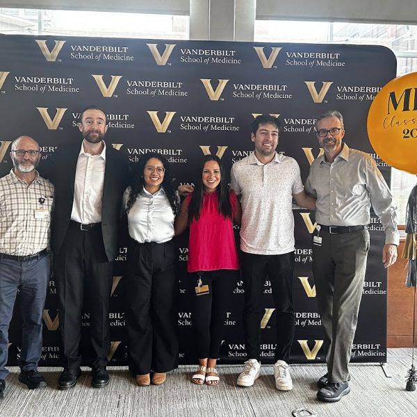Students pose with a balloon in front of a Vanderbilt backdrop to celebrate graduation.