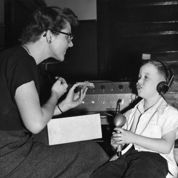 An unidentified therapist and child using equipment to aid with speech and hearing. Circa 1960s.